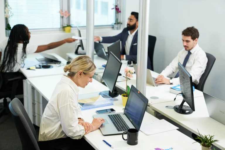 Équipe de professionnels travaillant dans un cabinet d'expertise comptable moderne, ordinateurs et open space