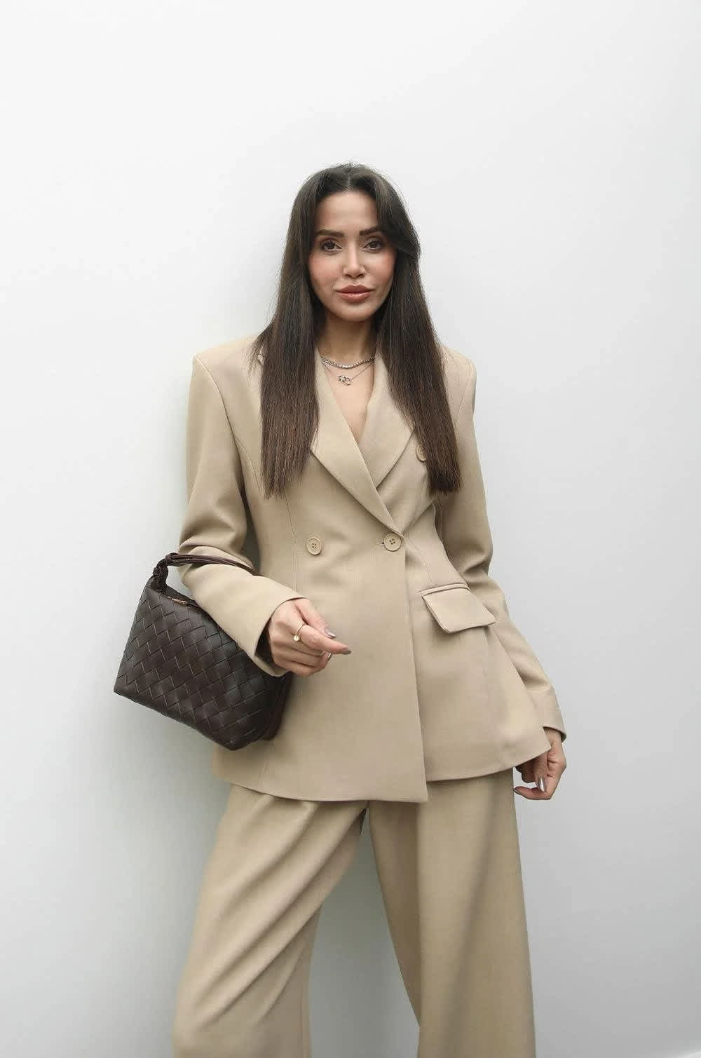 Beige tailored suit styled with a quilted luxury handbag
