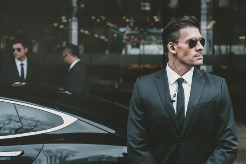 VIP protection officer standing by luxury car