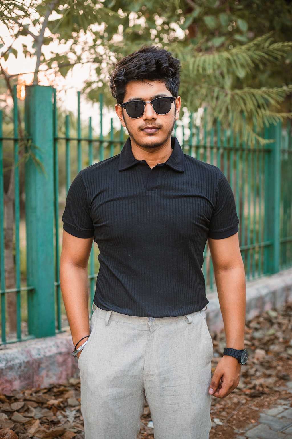 Man wearing black knitted polo t-shirt with light grey trousers - smart casual outfit
