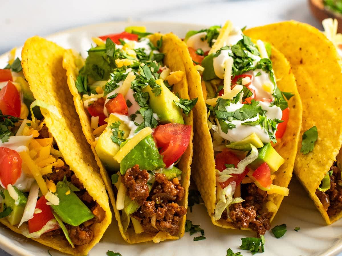 Beef tacos with avocado, tomatoes, and cheese on a plate