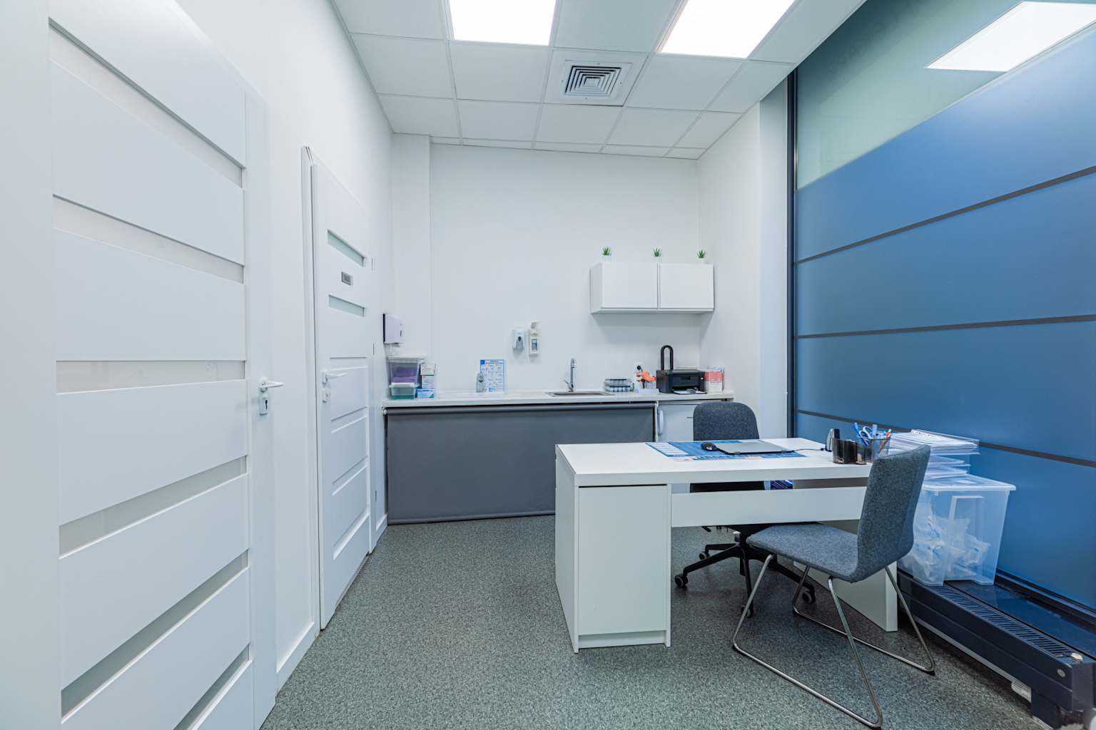 Nowoczesny gabinet medyczny w Polsce z biurkiem, krzesłami i sprzętem klinicznym