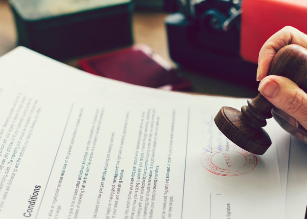 Рука ставить печатку на офіційному документі про дозвіл на роботу