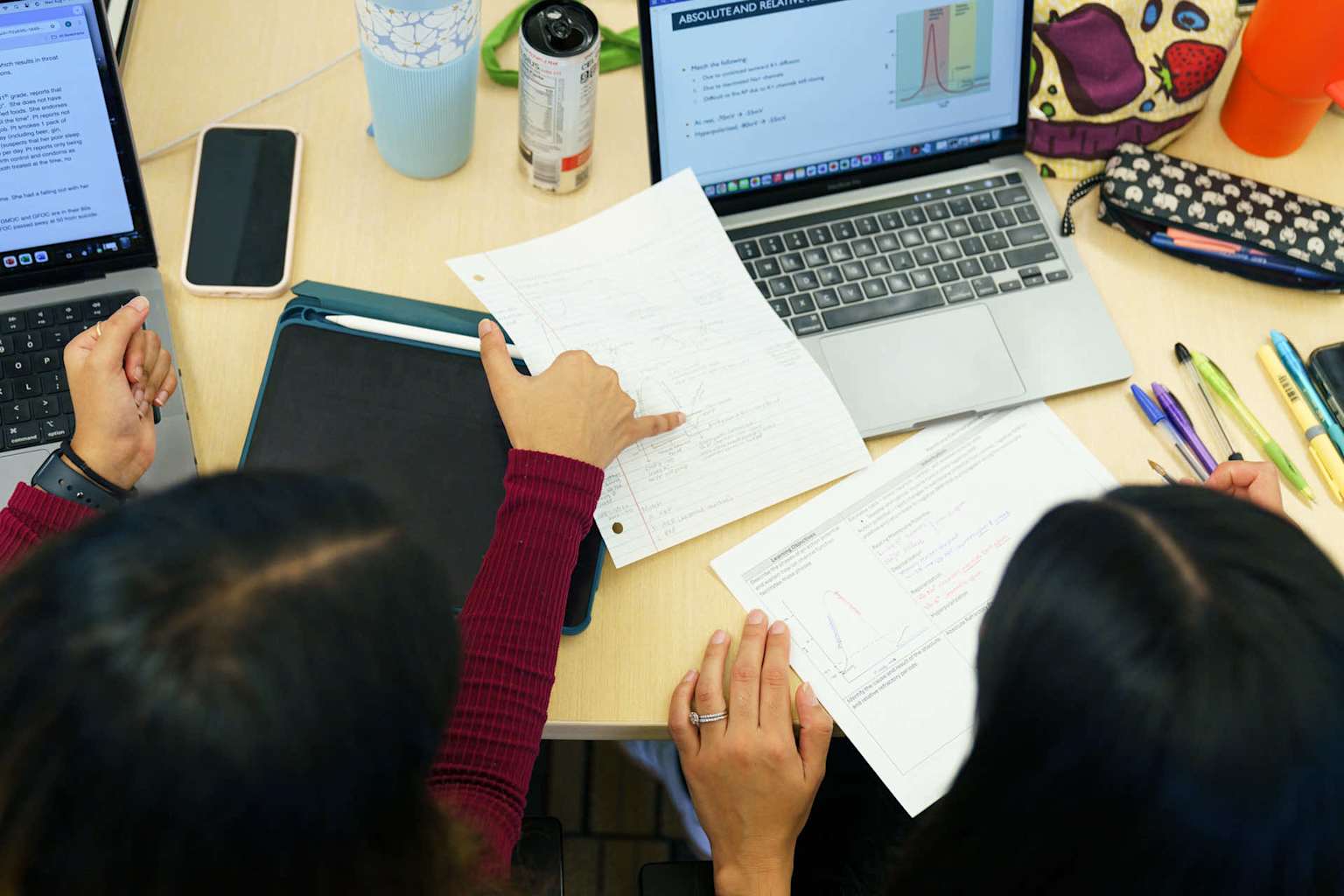 Dwie kobiety przeglądające dokumenty edukacyjne przy stanowisku administracyjnym