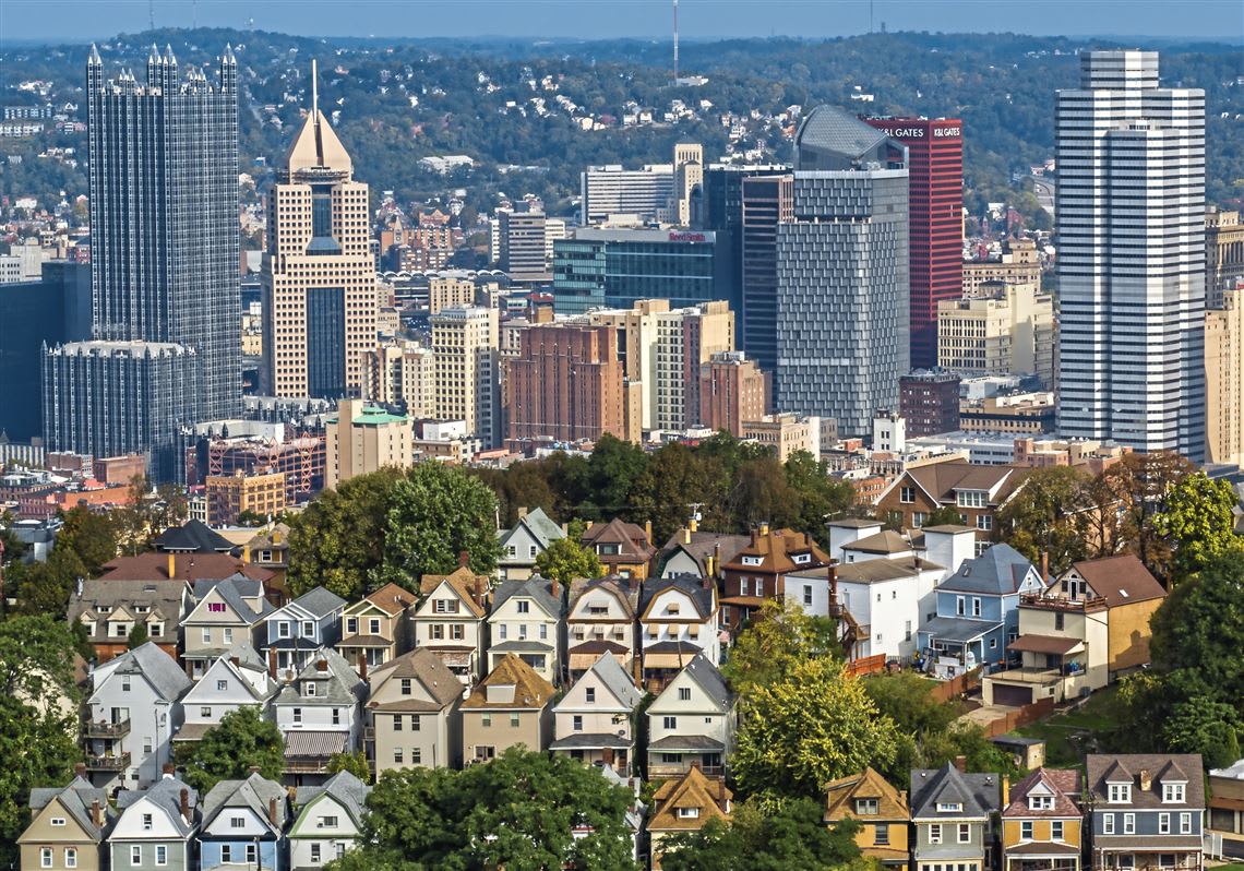 Aerial view of a Pittsburgh neighborhood with Victorian row houses and the city skyline