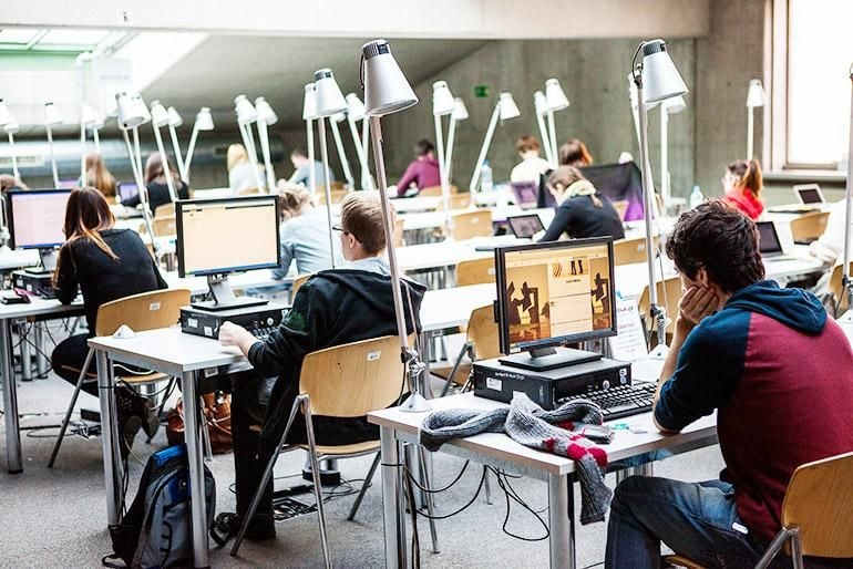 Studenci uczący się przy komputerach w bibliotece uniwersyteckiej