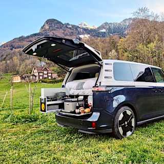 Volkswagen ID. Buzz showcasing flat sleeping configuration and built-in kitchenette for camping