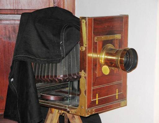 A 19th-century large-format studio plate camera on a wooden tripod.