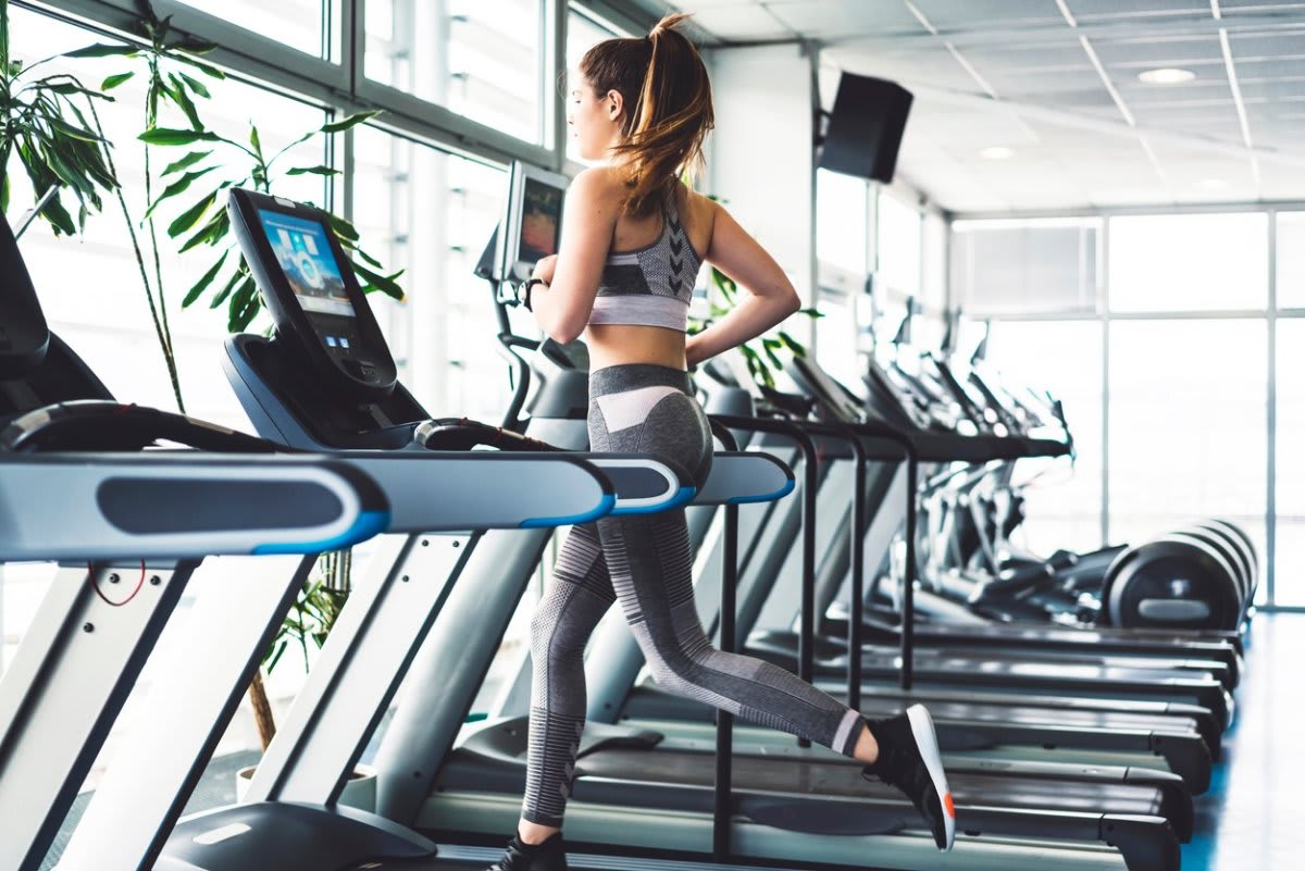 Woman running on a treadmill in a gym.