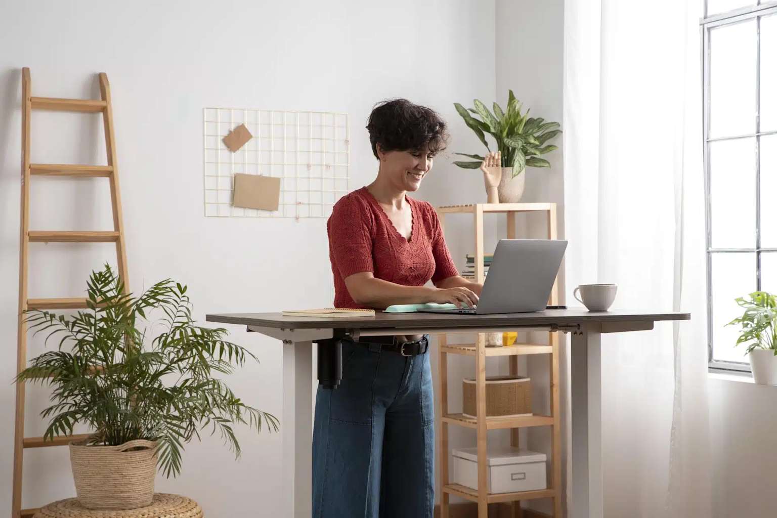 A woman working at an adjustable standing desk in a modern office.