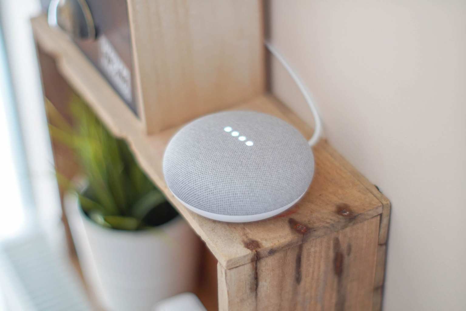A voice-activated smart home assistant, an example of an AI agent, on a wooden shelf.