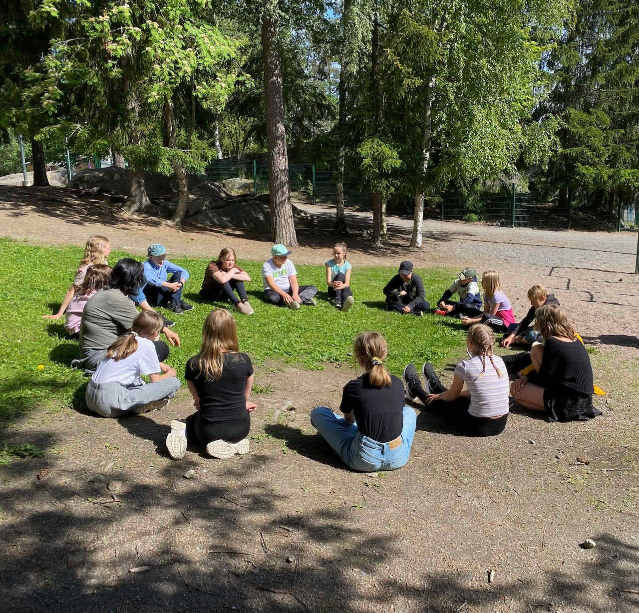 Children sit in a circle outside as part of an outdoor education program in Finland
