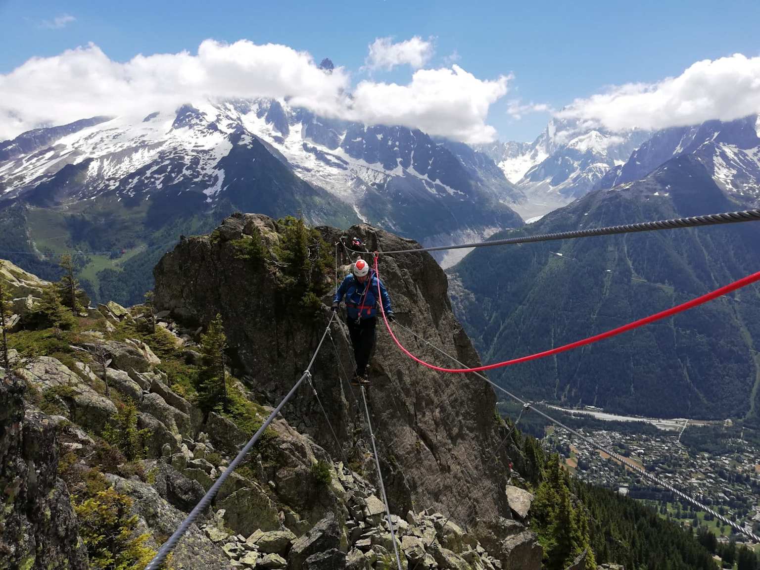 A climber crosses a cable bridge on the Flegere Via Ferrata in Chamonix, France