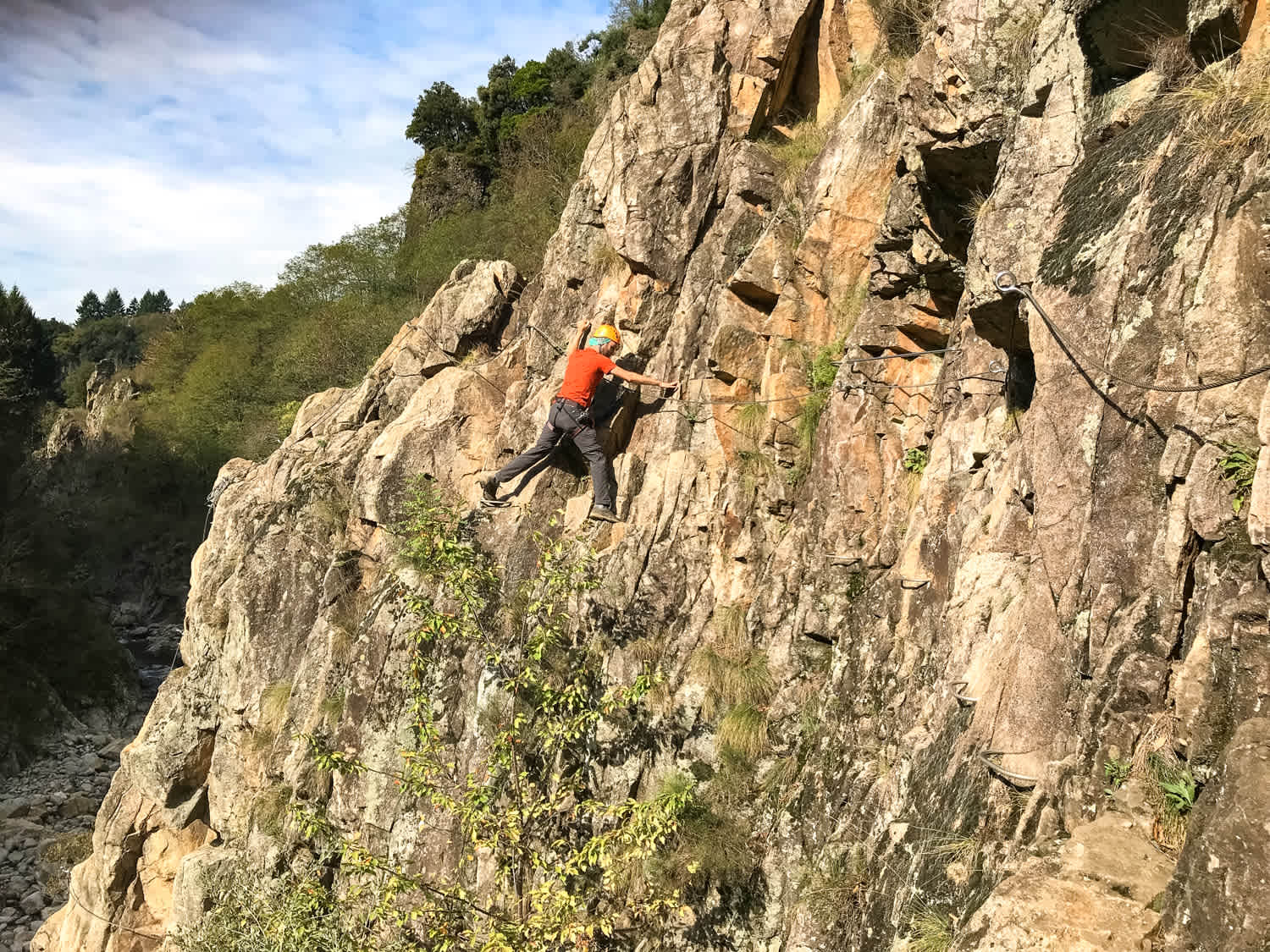 A climber navigates a via ferrata route on a rocky cliff