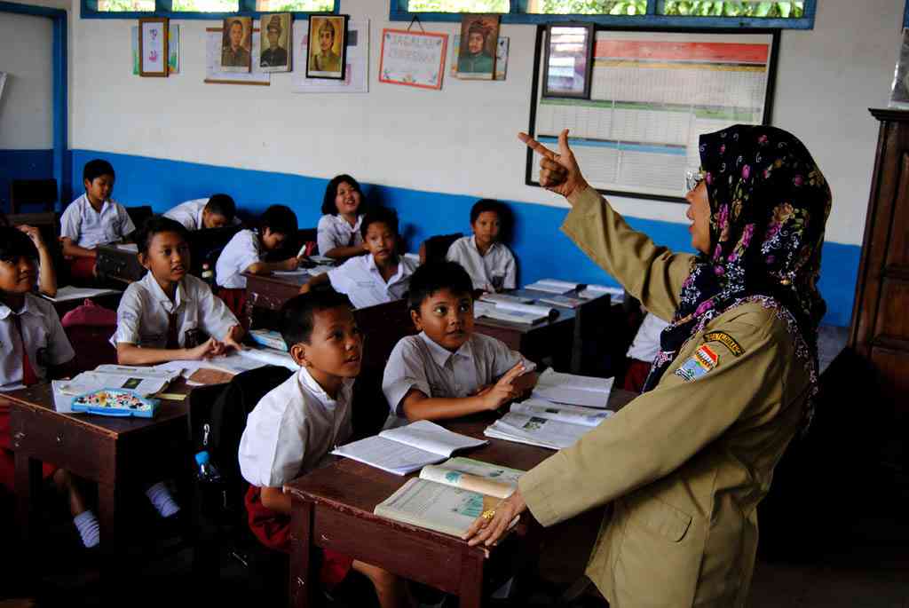 A teacher instructs students in an Indonesian classroom.