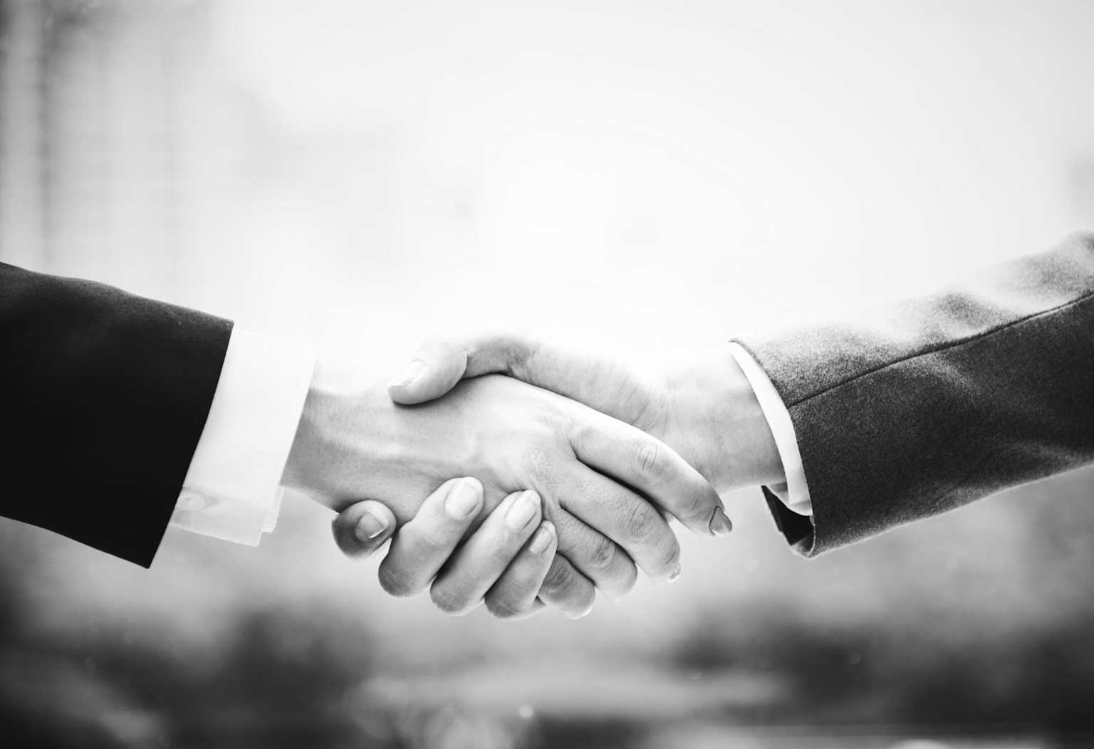 Black and white close-up of a professional handshake symbolizing business partnership and collaboration.