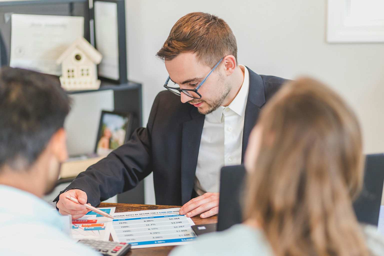 A real estate professional consults with clients, discussing financial details of a property transaction