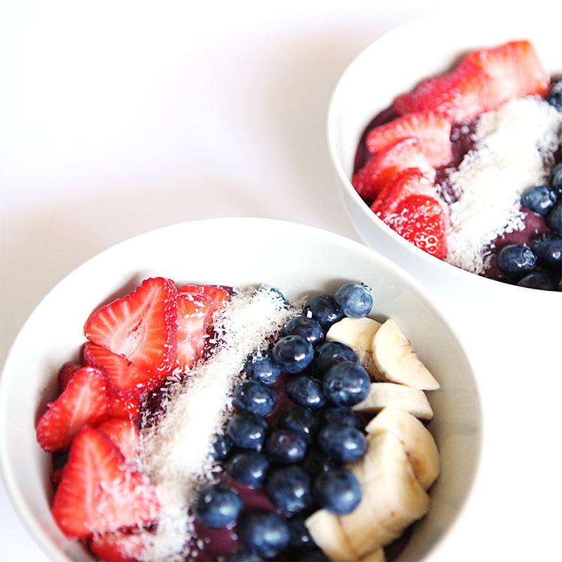 Bowls of açaí topped with strawberries, blueberries, bananas, and coconut