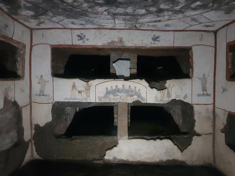 Interior of a chamber in the Catacombs of Callixtus, featuring burial niches and Christian frescoes