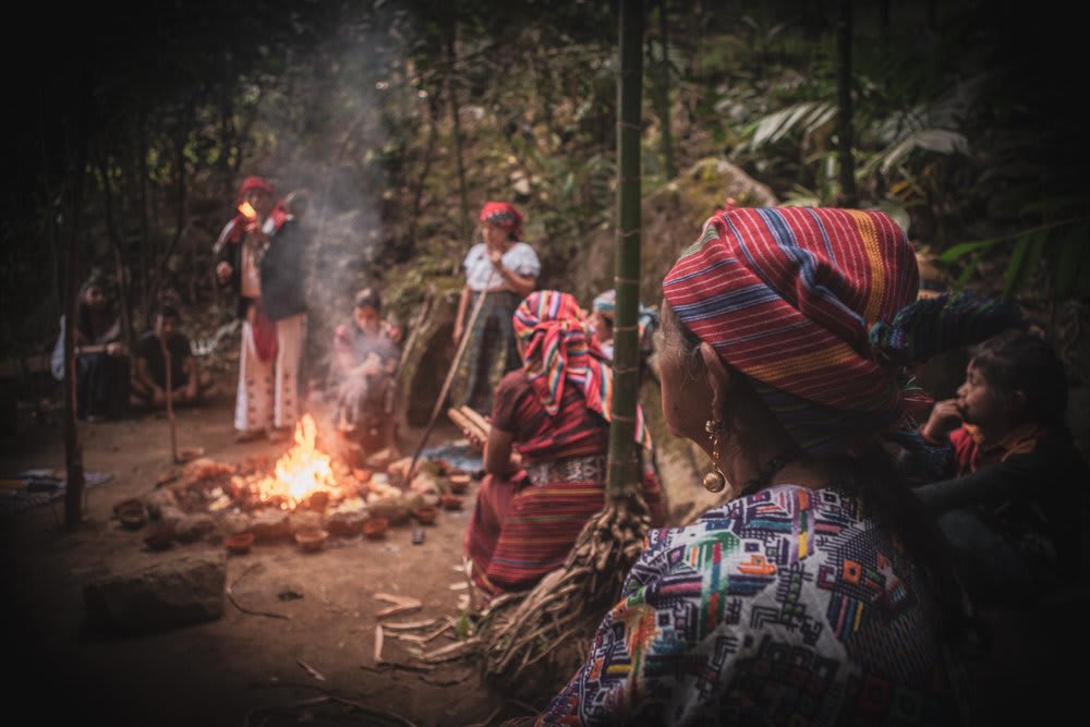 A group of people participating in a cacao ceremony around a fire