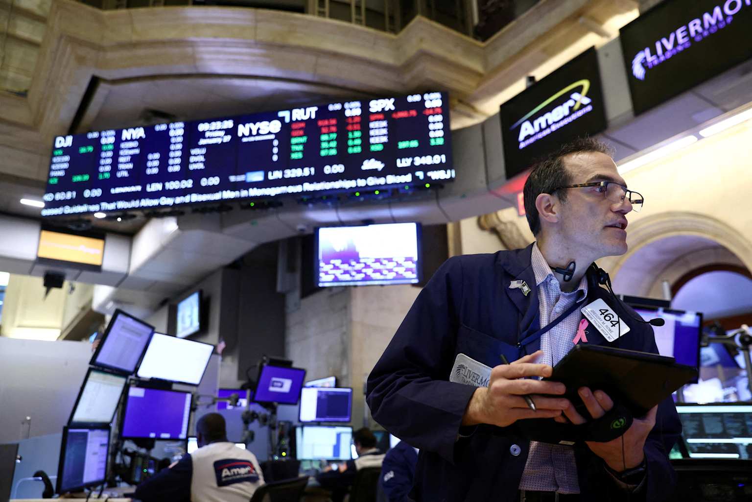 Stock market trading floor showing real-time stock indices and a trader actively monitoring market movements