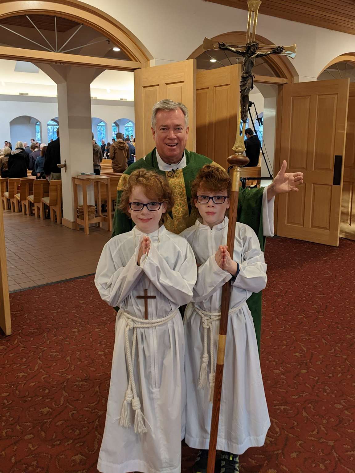Two altar servers pose with a priest inside a church