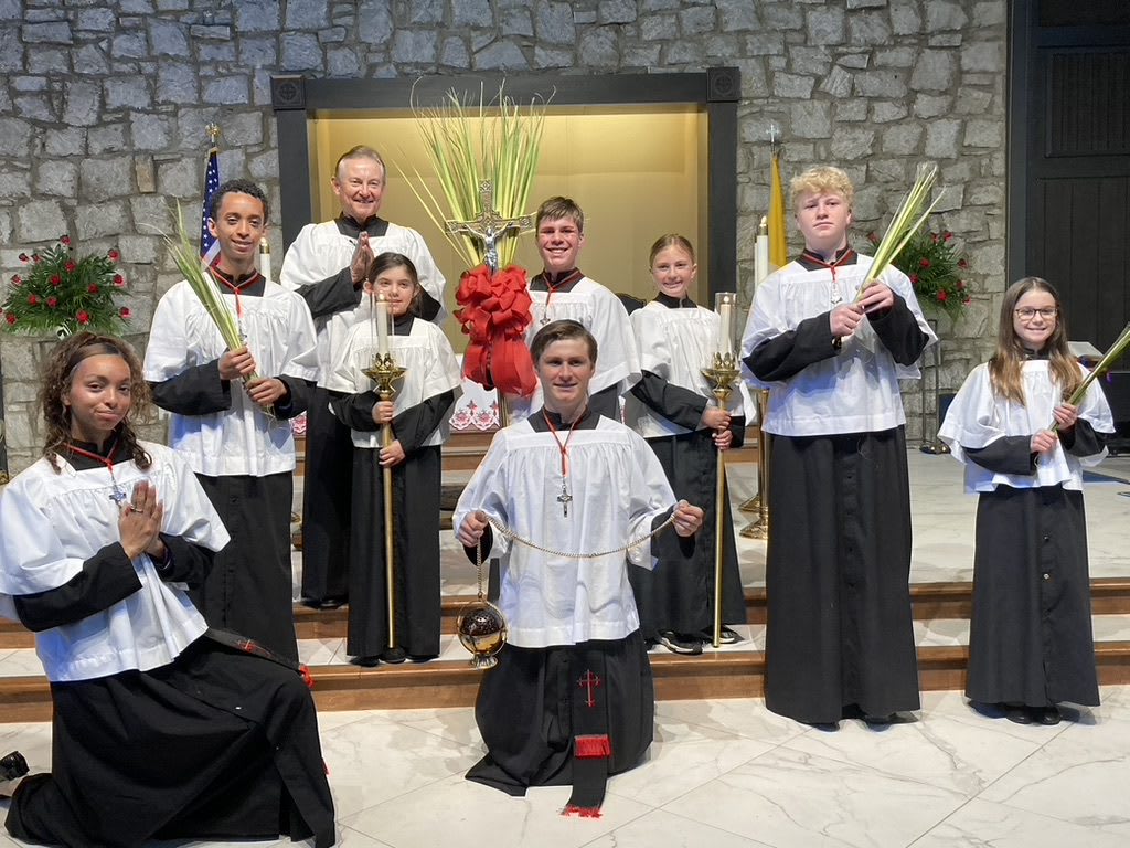A group of altar servers with a priest in a Catholic church