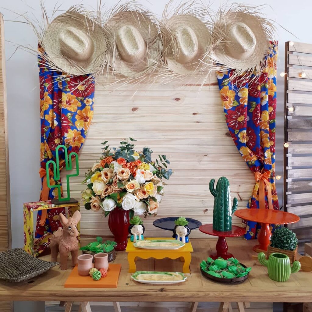 A festive table setting decorated with straw hats, floral fabric, and rustic elements, embodying the spirit of Festa Junina