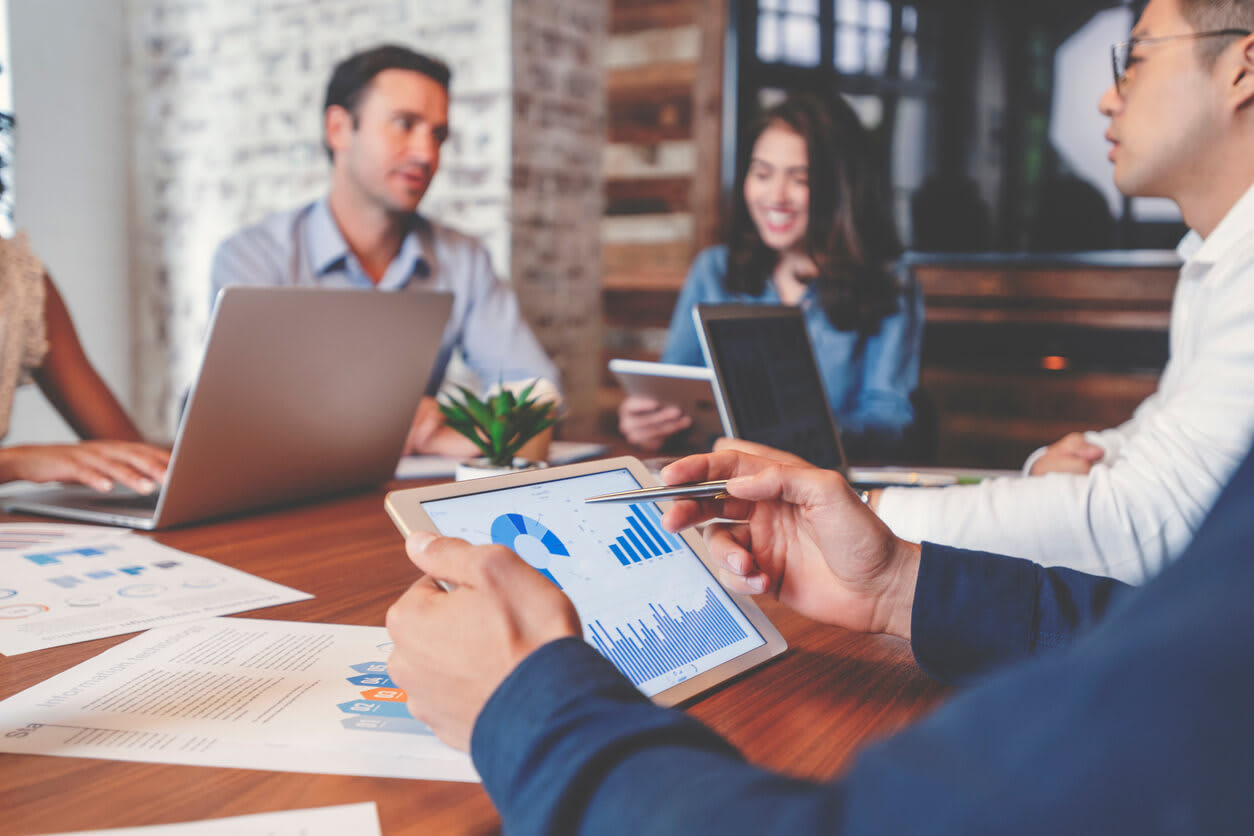 Professionals analyzing financial data and charts on a tablet during a business meeting