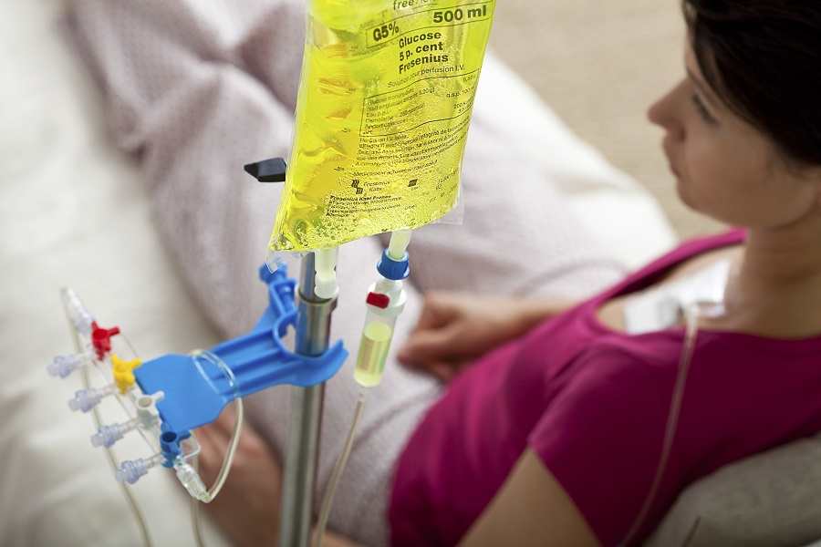 A patient receives an intravenous infusion, likely chemotherapy, through a central venous access device