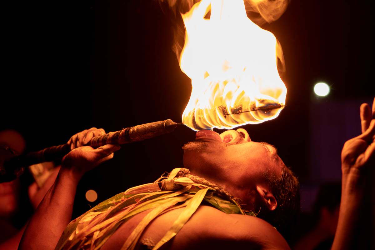 Traditional Hawaiian fire dancer performing a fire-eating act during a luau cultural show at night
