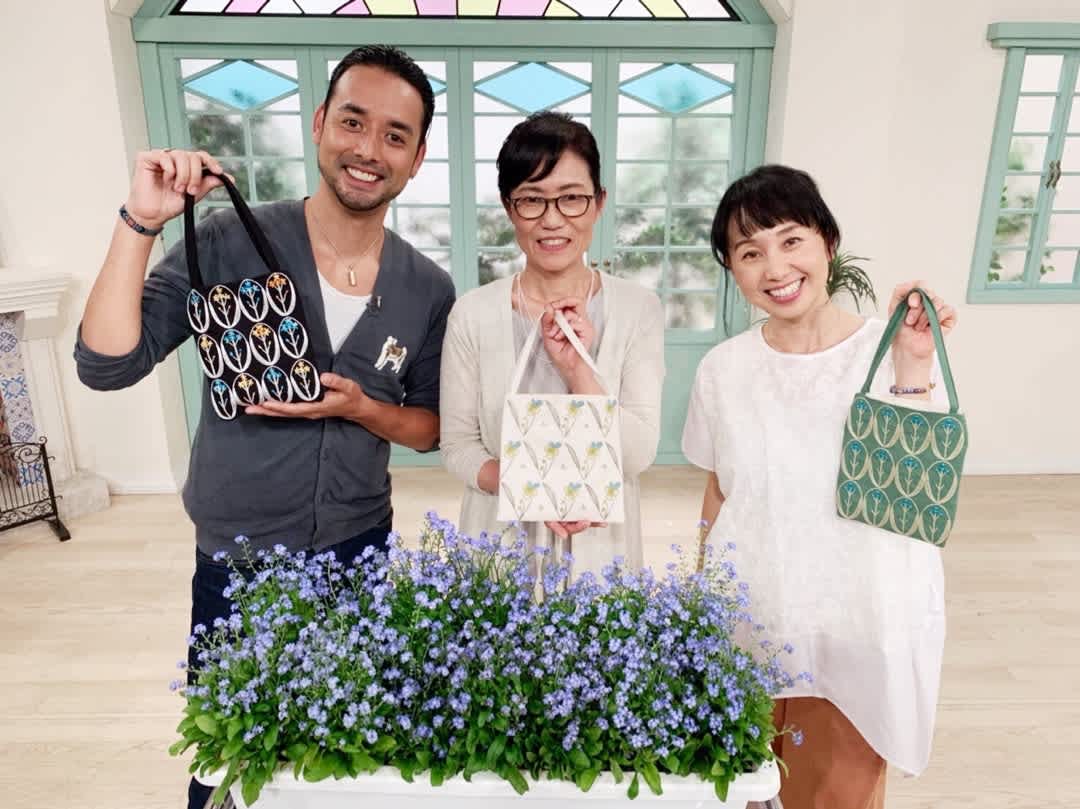 Three people proudly display hand-embroidered floral handbags, highlighting the craft featured in NHK's "すてきにハンドメイド" with 勝野洋輔