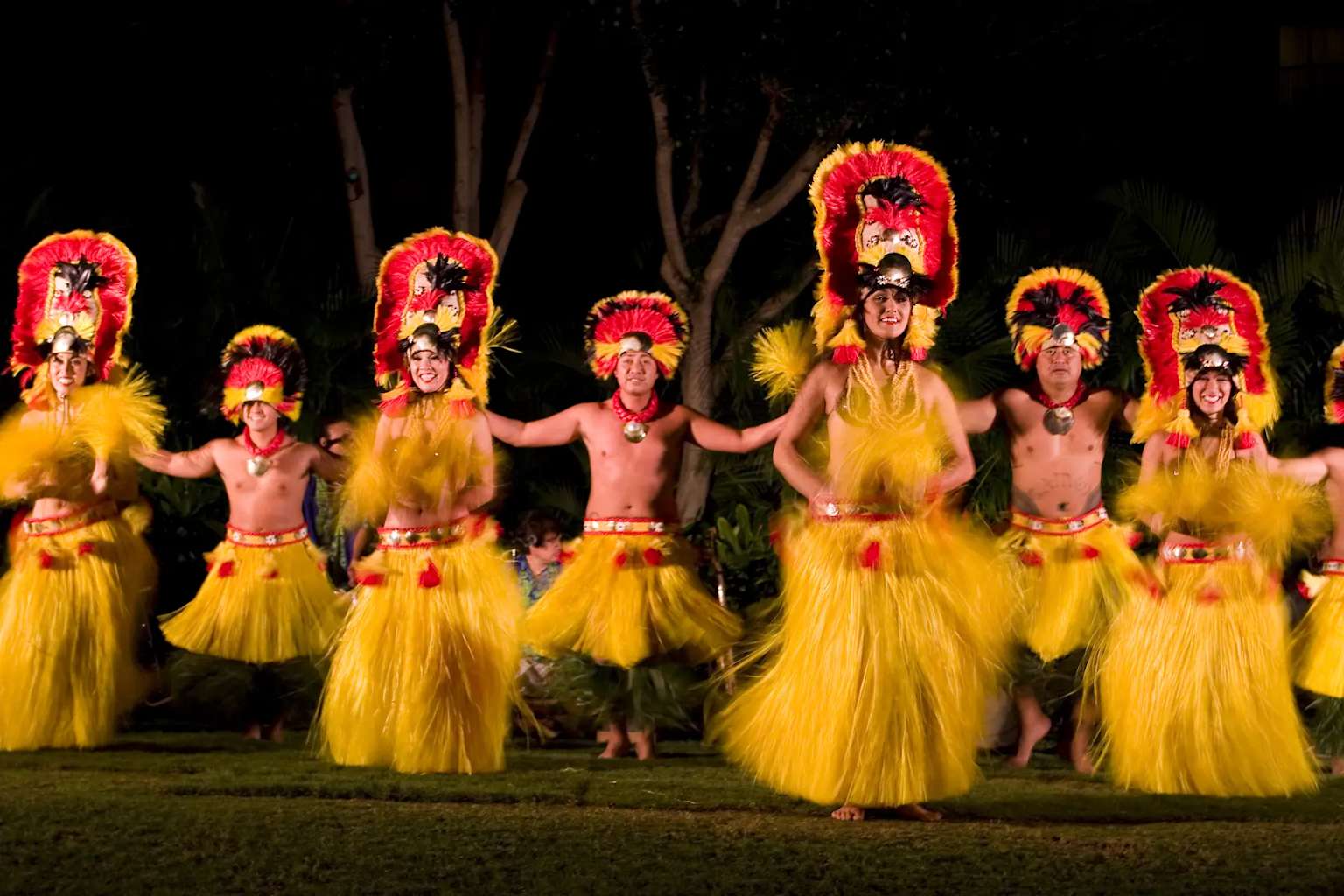 Performers in vibrant traditional attire at a Hawaiian cultural show
