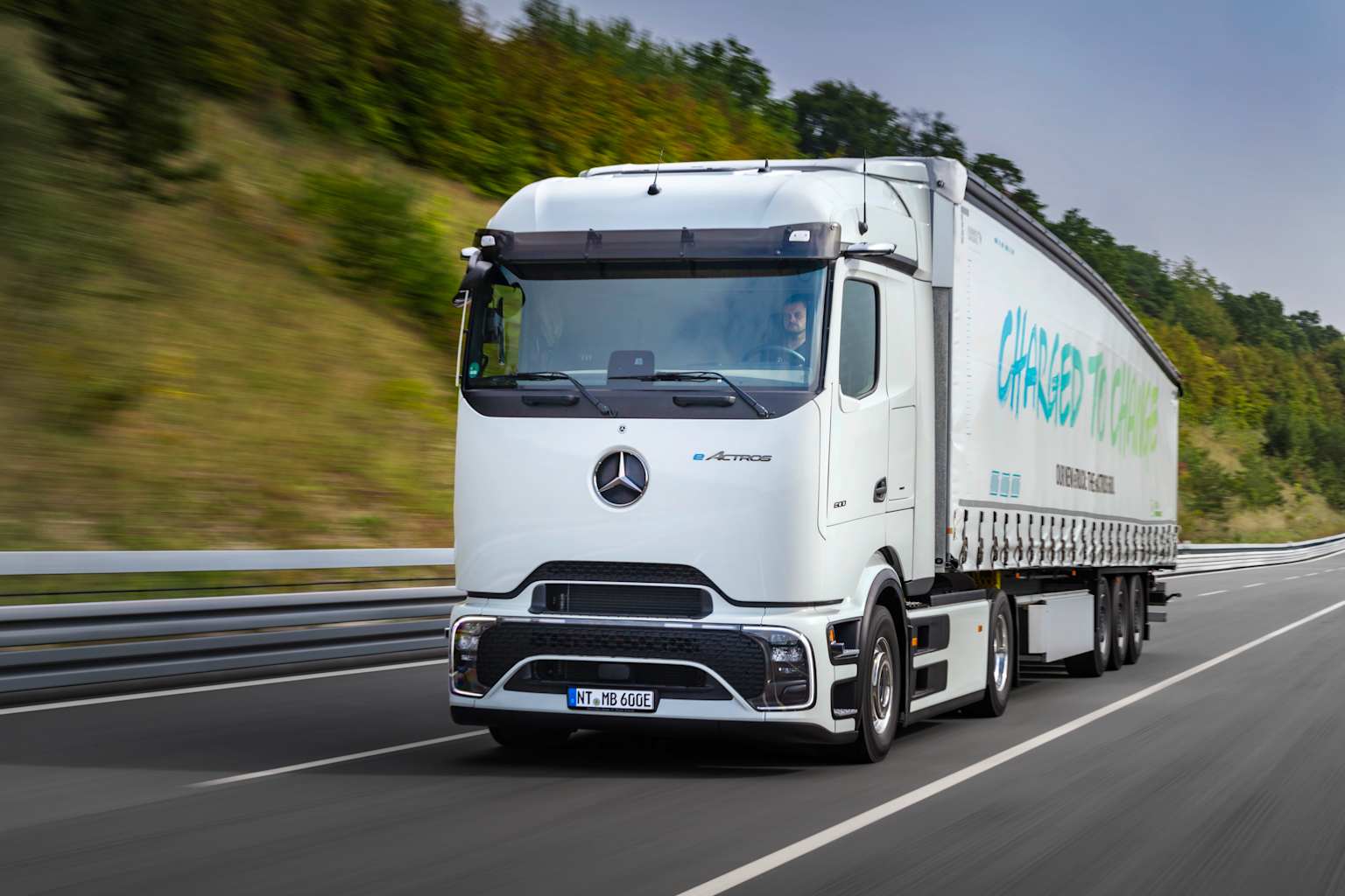 A white Mercedes-Benz eActros electric truck transporting goods on a highway, representing modern road freight solutions