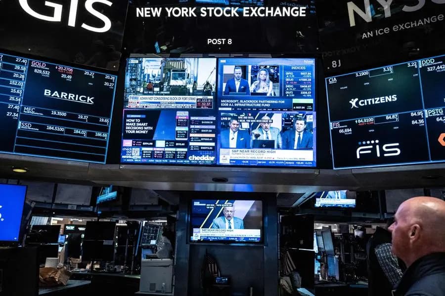 A large screen on the New York Stock Exchange trading floor displays "GOLD" with a positive price change, amidst other financial market data