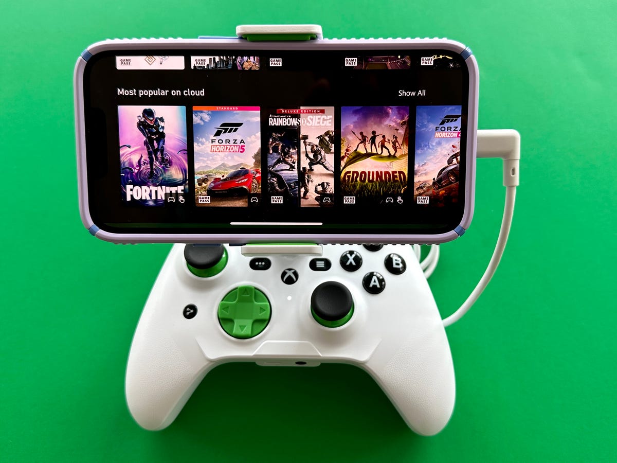 A smartphone displaying a cloud gaming interface with titles like Fortnite and Forza Horizon, mounted on a white Xbox-style controller.