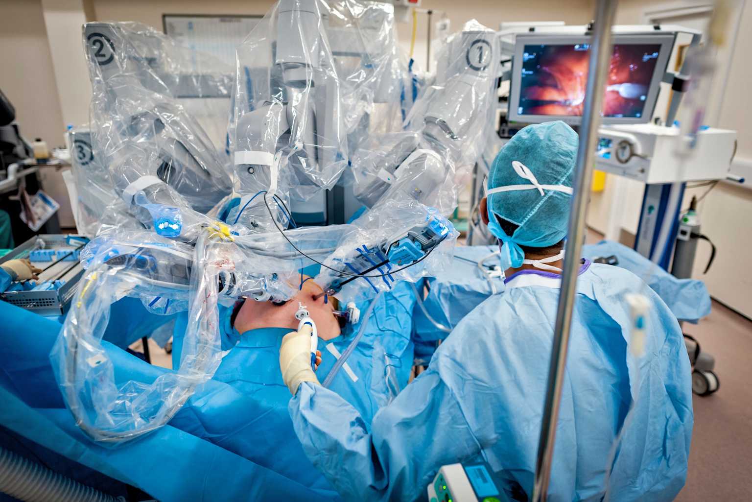 A Da Vinci surgical robot performs a minimally invasive procedure on a patient in an operating room