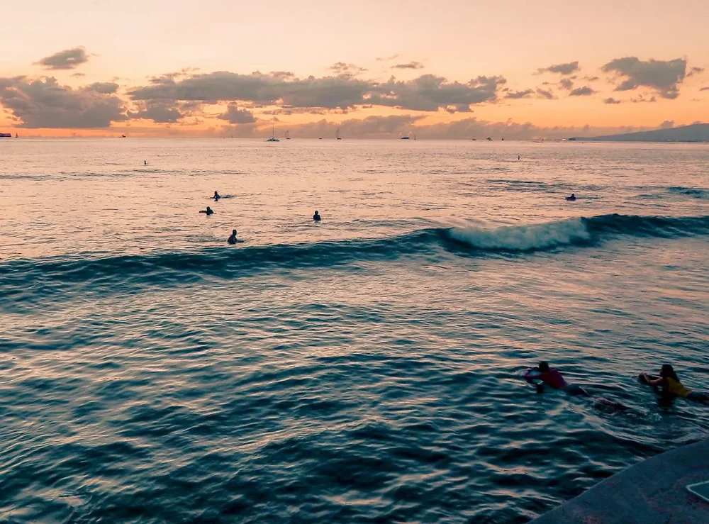 Surfers enjoying the sunset at Waikiki Beach in Oahu