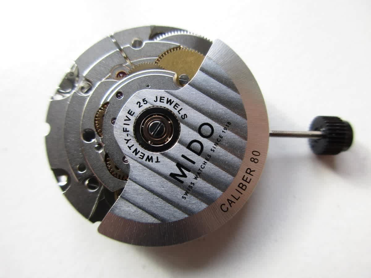 A close-up view of the Mido Caliber 80 automatic watch movement, highlighting its intricate components and brand inscriptions