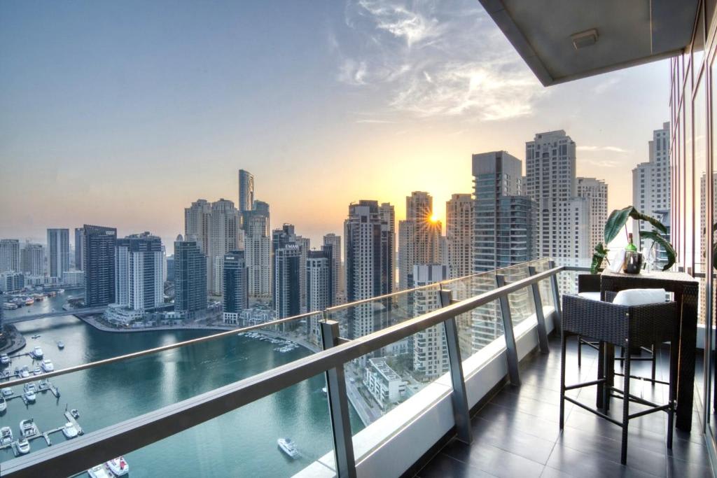 A luxurious penthouse balcony offers a sunset view of the modern Dubai Marina skyline and its bustling waterfront