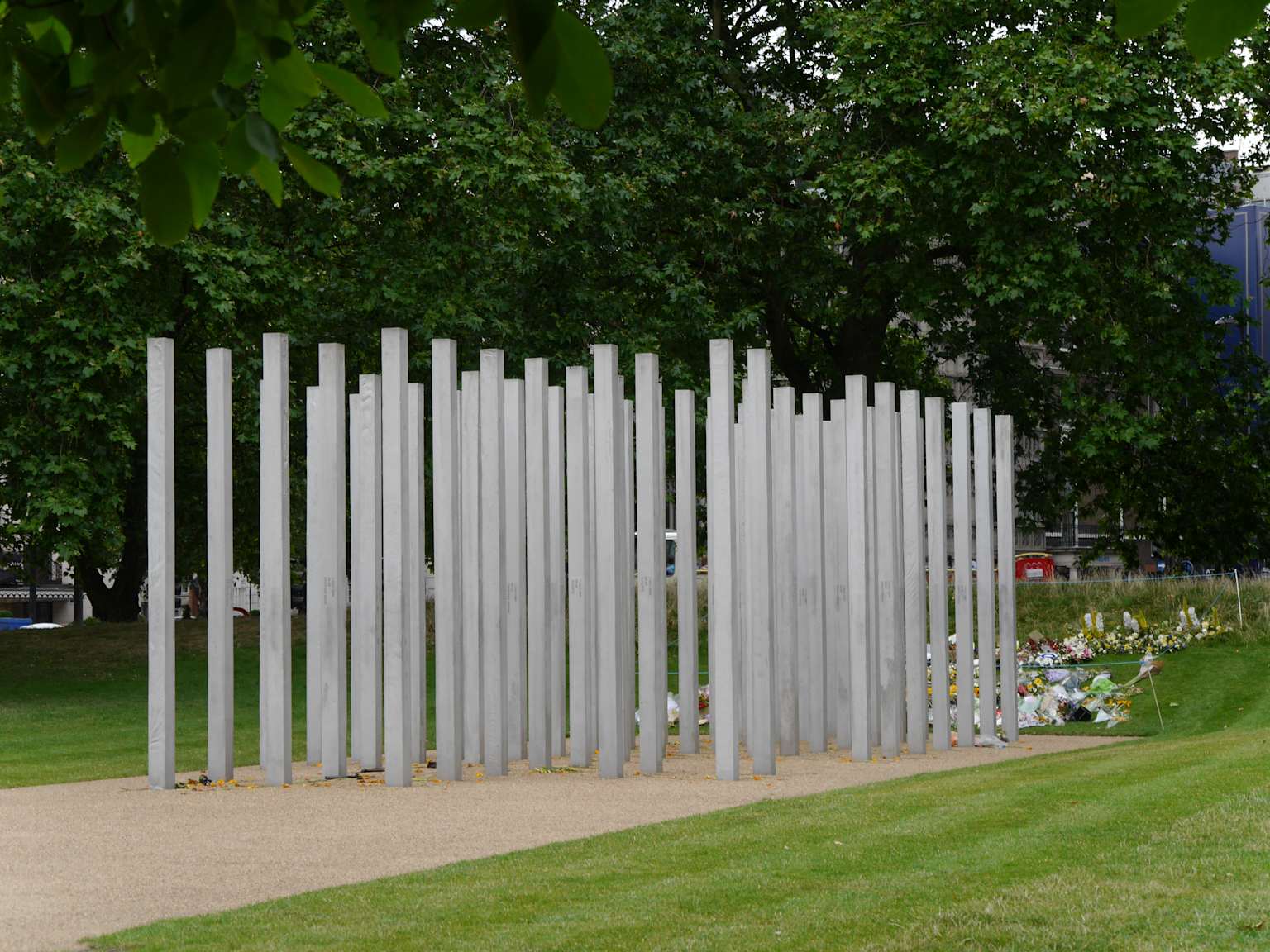 The 7/7 London Bombings Memorial in Hyde Park, with floral tributes at its base, commemorating the victims of the 2005 attacks