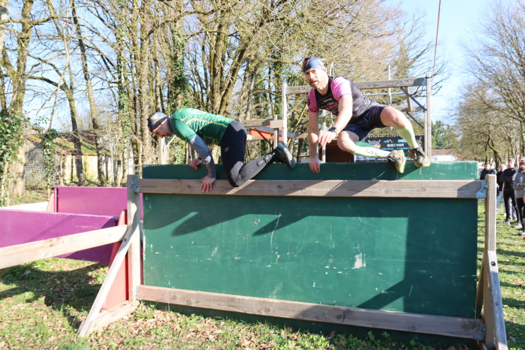 Athletes navigate a wall obstacle during an outdoor obstacle course race