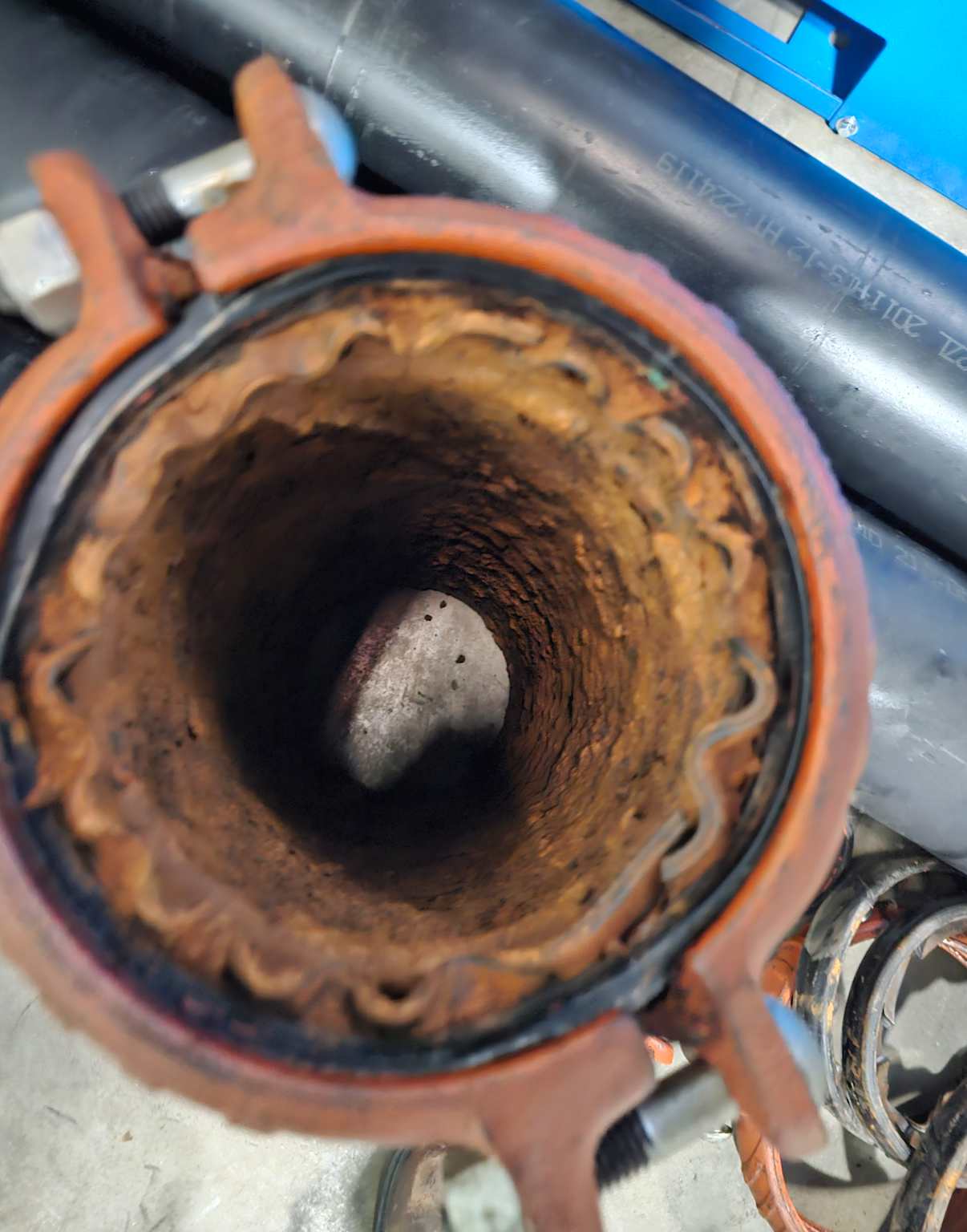 Corroded interior of a compressed air pipe showing severe rust and buildup