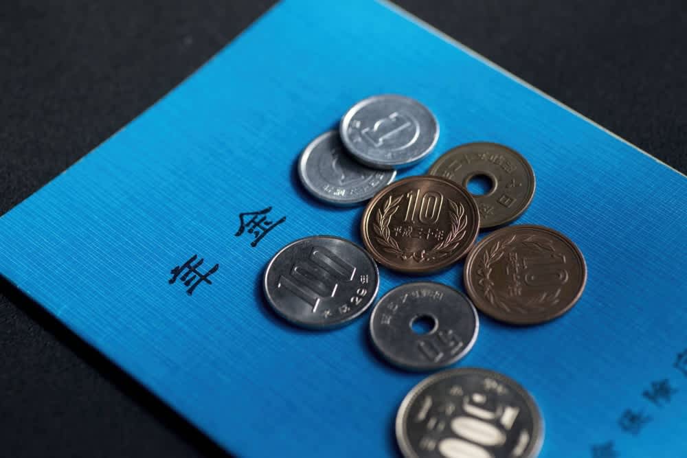 Japanese yen coins on a blue pension book symbolize financial planning and long-term savings