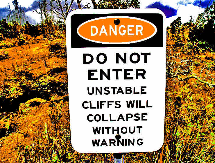 A warning sign advises visitors about the danger of unstable cliffs that could collapse without warning