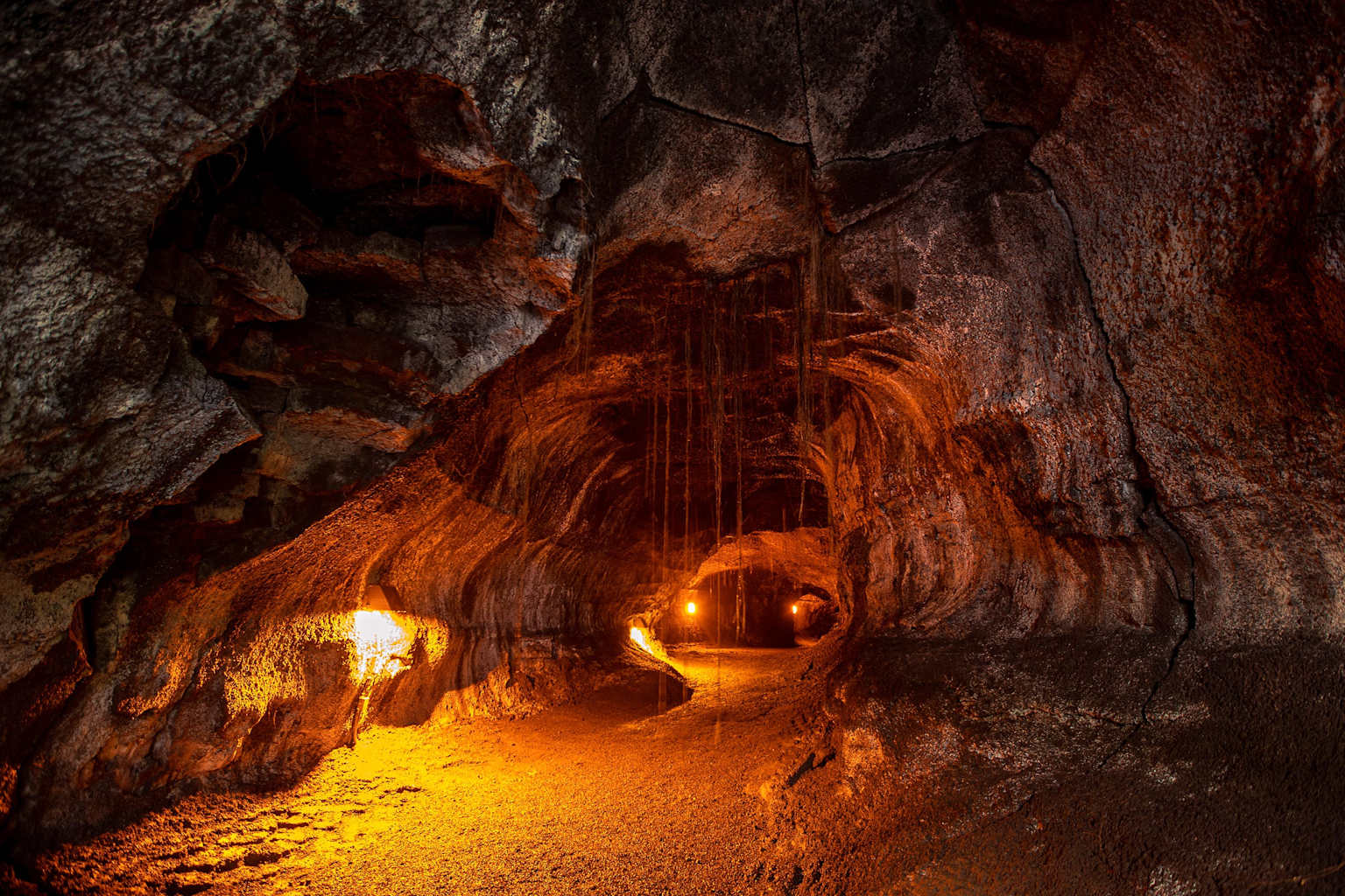 Interior view of the Nahuku lava tube in Hawaii Volcanoes National Park showcasing its unique volcanic rock formations and warm lighting