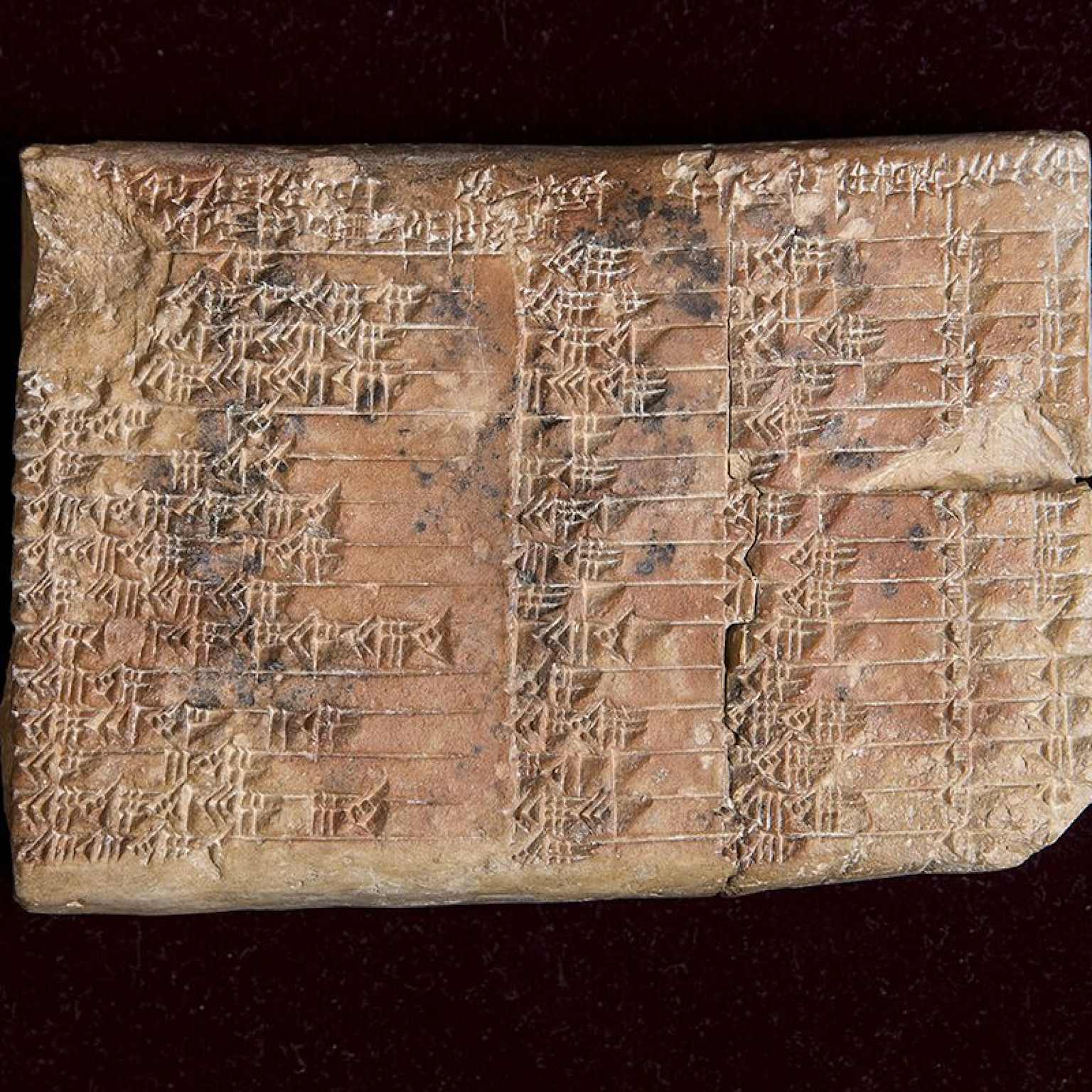 Ancient Babylonian clay tablet inscribed with cuneiform script, representing the historical use of a base-60 number system.