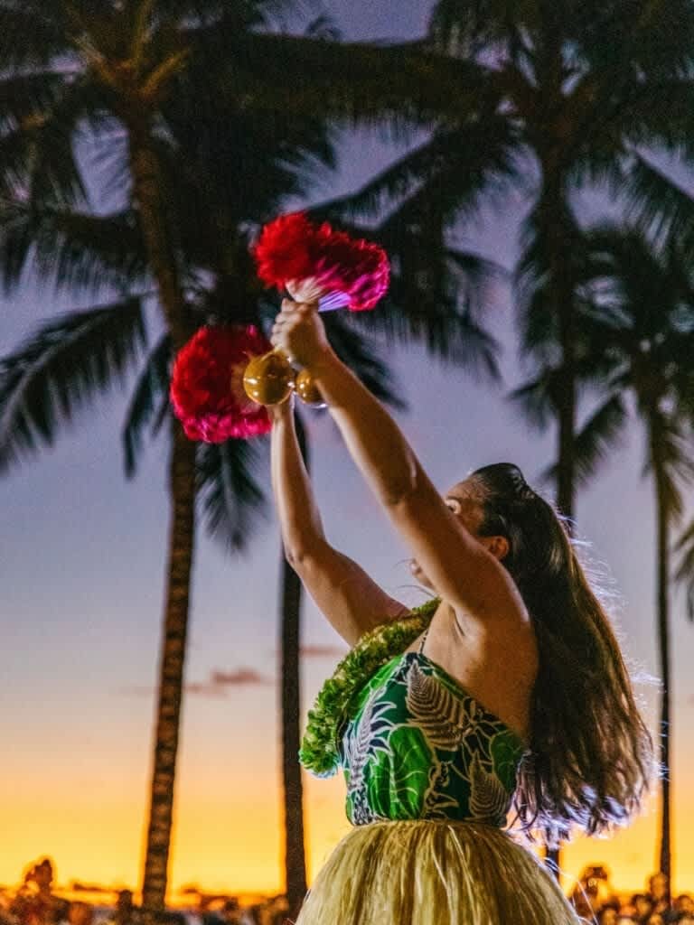 A hula dancer performs with uli'uli at sunset, a beautiful example of free cultural experiences in Hawaii