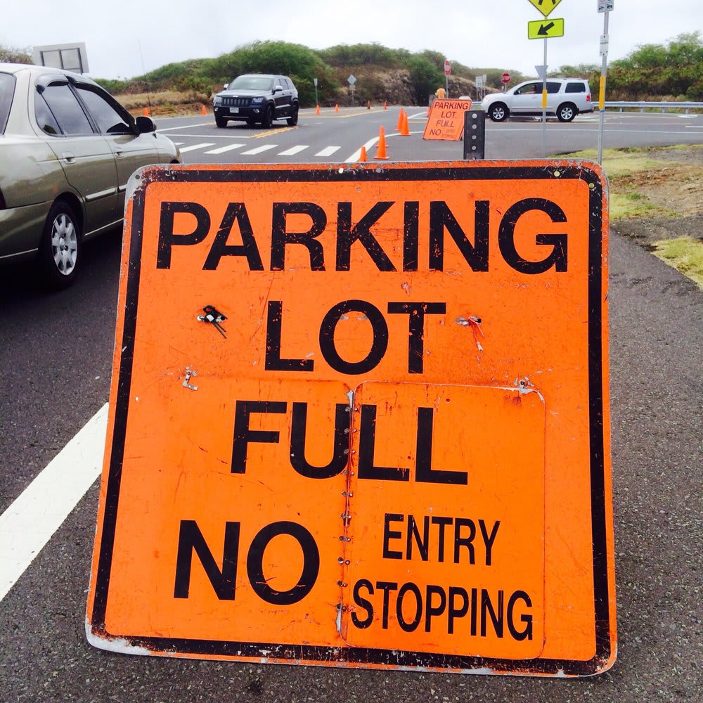 A portable orange sign clearly indicates that the parking lot is full, prohibiting entry and stopping