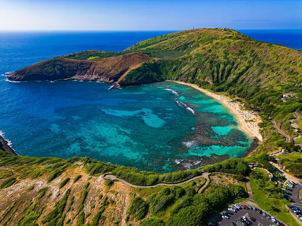 An aerial view captures the vibrant turquoise waters and bustling parking lot of Hanauma Bay